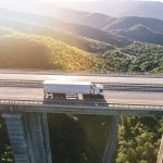 Ciężarówki na tle magazynu – firma transportowa z Bydgoszczy oferuje kompleksową obsługę przewozów dla firm w Polsce i za granicą.