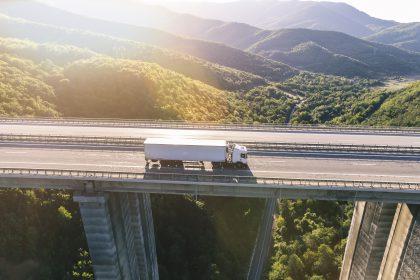 Ciężarówki na tle magazynu – firma transportowa z Bydgoszczy oferuje kompleksową obsługę przewozów dla firm w Polsce i za granicą.