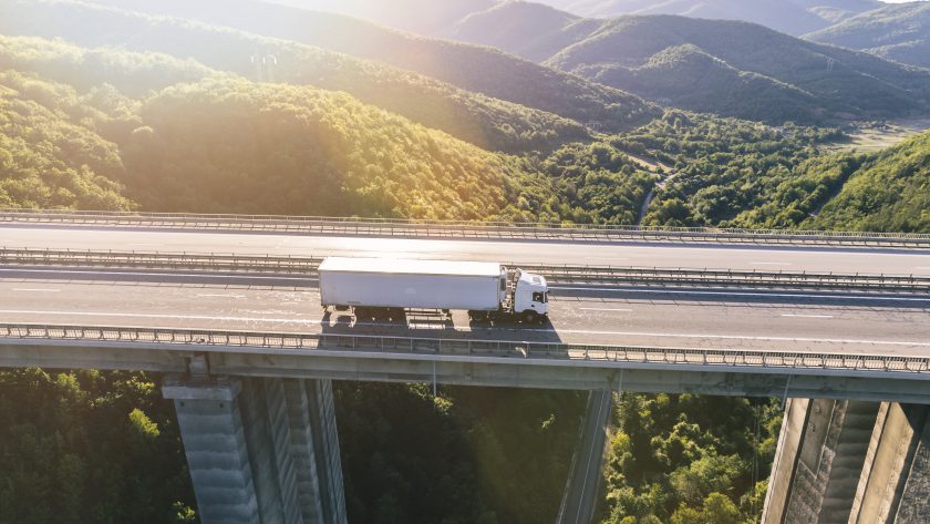 Ciężarówki na tle magazynu – firma transportowa z Bydgoszczy oferuje kompleksową obsługę przewozów dla firm w Polsce i za granicą.